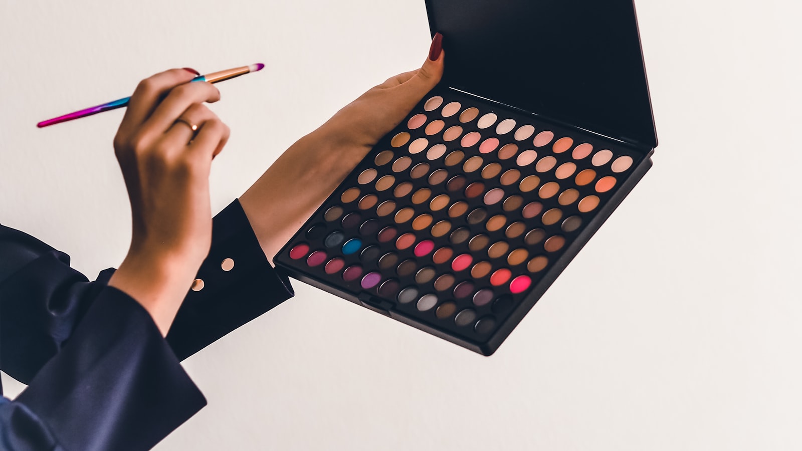 A blush compact and brush beside a soft pink cheek color swatch