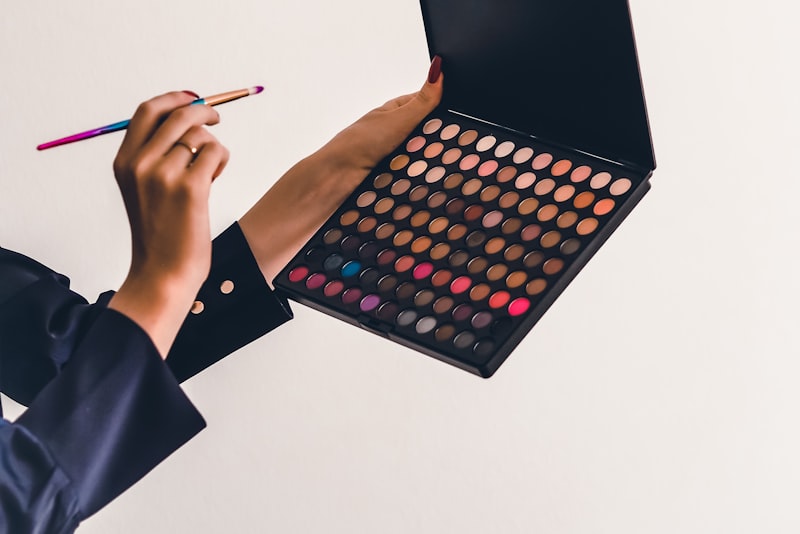 A blush compact and brush beside a soft pink cheek color swatch