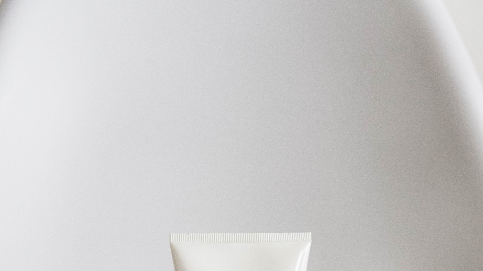 A small dropper bottle of clear serum resting on a soft neutral background